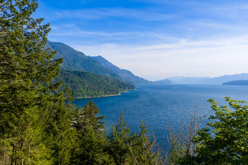 Fototapeta premium Panoramic View of Harrison Lake With Forested Mountains and Calm Blue Water in British Columbia
