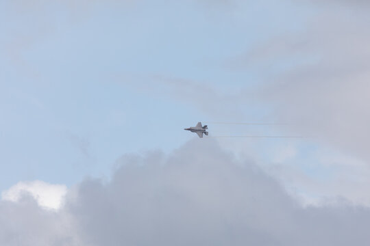 American 5th generation stealth fighter jet of the US Air Force performing aerial maneuvers in cloudy skies. Powerful modern military aircraft flying during aviation demonstration
