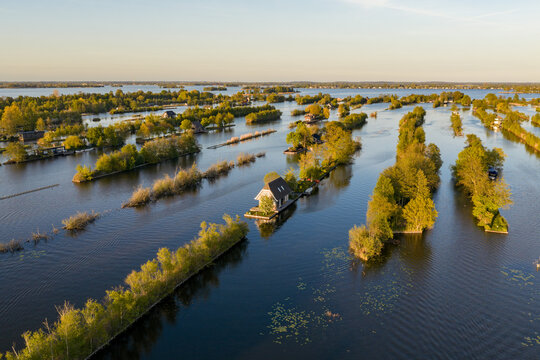 Breukelen, Netherlands - 25 April 2026: Aerial view of the Scheendijk recreational area with narrow islands and small houses surrounded by calm water and lush greenery.