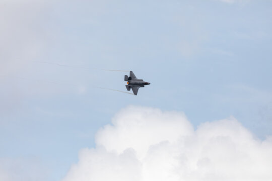American 5th generation stealth fighter jet of the US Air Force performing aerial maneuvers in cloudy skies. Powerful modern military aircraft flying during aviation demonstration