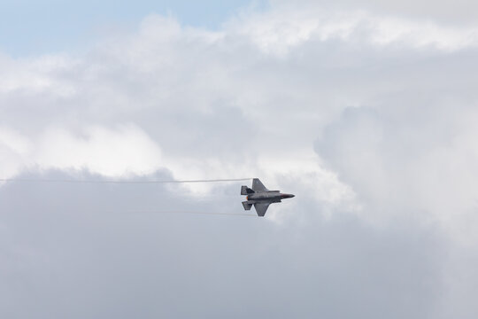 American 5th generation stealth fighter jet of the US Air Force performing aerial maneuvers in cloudy skies. Powerful modern military aircraft flying during aviation demonstration
