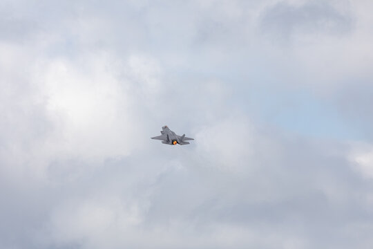 American 5th generation stealth fighter jet of the US Air Force performing aerial maneuvers in cloudy skies. Powerful modern military aircraft flying during aviation demonstration