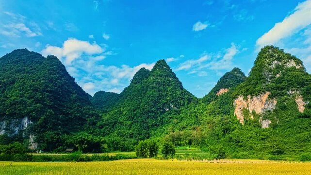 The countryside glows in the fading light as haystacks rest in open fields, framed by majestic mountains and a dramatic evening sky, creating a serene yet powerful scene of nature and tradition.