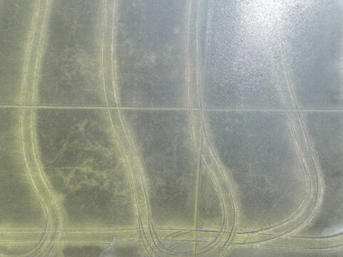 Aerial view of flooded agricultural fields with curved tire tracks and reflective water surfaces in the countryside Trino, Piedmont, Italy.