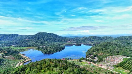 Fototapeta premium Aerial view of a serene lake surrounded by lush green mountains and trees.