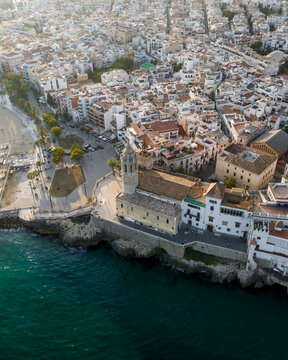 Aerial view of the Church of San Bartolome and Santa Tecla overlooking the Mediterranean Sea and the white-walled old town in Sitges, Catalonia, Spain.