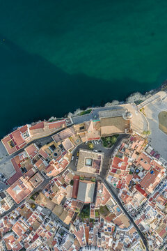 Aerial view of the historic center with terracotta rooftops, the Church of Sant Bartomeu i Santa Tecla, and the deep blue Mediterranean Sea Sitges, Catalonia, Spain.