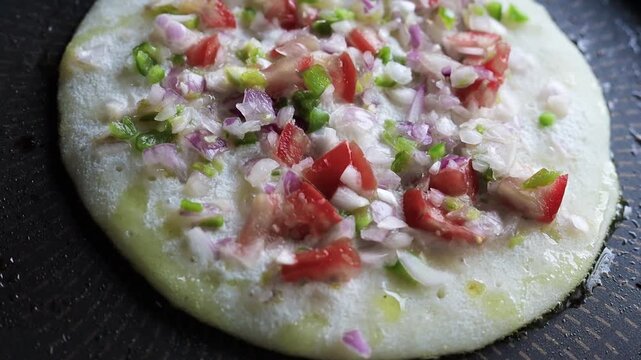 Indian chilla or uttapam prepared on black pan in kitchen