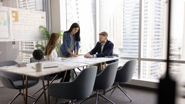 Group of startup founders gathered around conference table, collaborating on business plan and pitch decks, reviewing market strategies, working together on financial forecast, analyzing sales data