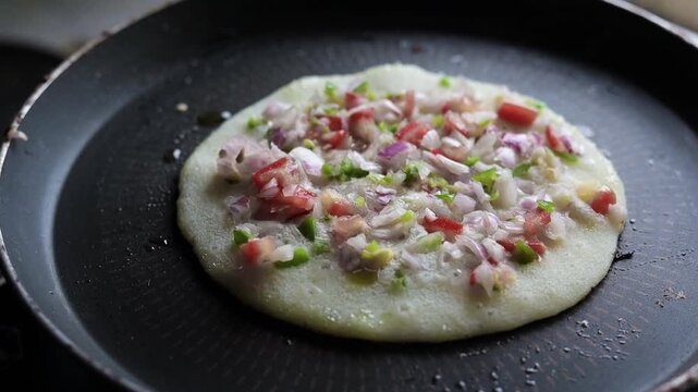 Indian chilla or uttapam prepared on black pan in kitchen