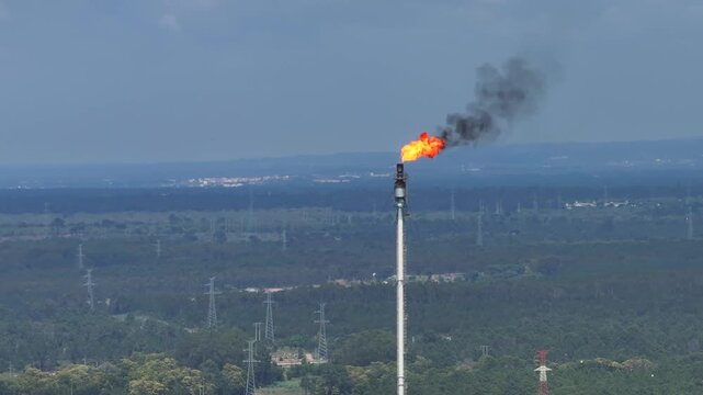 High above the oil refinery, flames ignite from the flare stacks, signaling the vital process of converting crude oil into fuel.