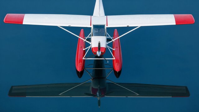 floatplane. Top-down view of a floatplane's wing and red floats on calm water. mobility guides, transit brochures, designed for transport & logistics marketing, improves user orientation.