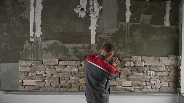 Inspection Of Stone Veneer. Worker Carefully Measures And Plans Interior Stone Wall Arrangement