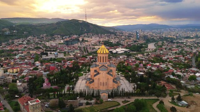 aerial wide angle drone  of the Holy Trinity Cathedral of Tbilisi (Sameba) at sunset. Georgian Orthodox church with the city skyline in the background
