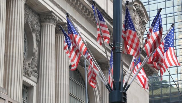 American flags near Grand Central Terminal on 42 street, New York City, Manhattan Midtown. Railway building architecture in United States. Public railroad transport junction. Old station exterior.