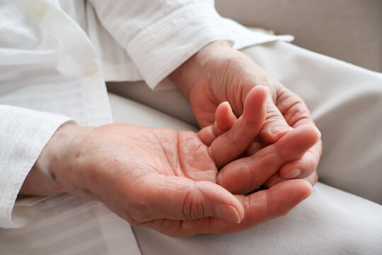 A senior woman's hand touching her finger joints.