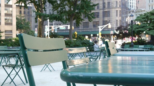 Fifth 5 avenue and Broadway street crossroad, Manhattan Midtown, New York City, United States. Defocused people pedestrians, chairs and tables for picnic in Madison Square Park, Flatiron District .