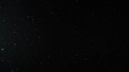 Slow motion real dust particles floating mid air over dark background