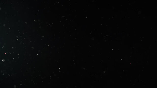 Slow motion real dust particles floating mid air over dark background