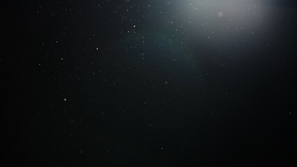 Slow motion real dust particles floating mid air over dark background