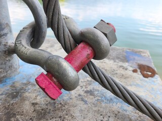 a heavy-duty steel wire rope connected to a metal shackle with a bright pink bolt. This industrial...