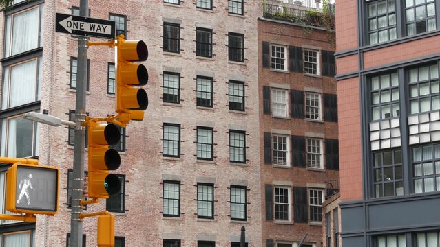 New York City Lower Manhattan, United States. Urban road sign of american street, traffic sign in NYC. Red brick building architecture, Tribeca district. One way arrow and yellow traffic light.