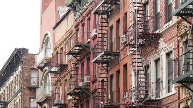 New York City urban residential buildings architecture, Manhattan classic street, United States of America. Typical red brick house in NYC, real estate property in USA. Fire escape metallic ladder.
