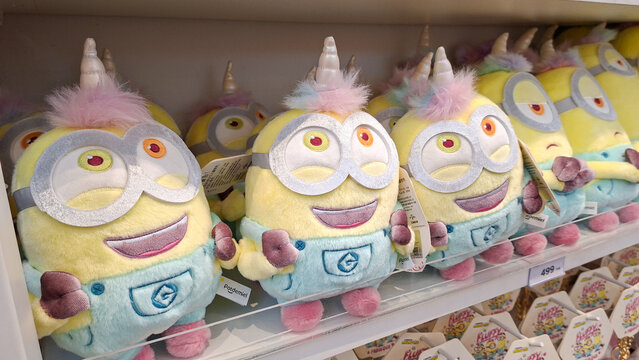 Row of smiling Minions plush toys featuring unicorn horns and fluffy pink hair displayed on store shelf on May 8, 2026 in Bangkok, Thailand.