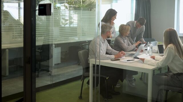 Creative business people, planning and meeting and brainstorming, ideas or strategy at office, view from glass wall.