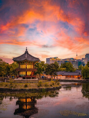 Obraz premium Hyangwonjeong Pavilion at Gyeongbokgung Palace during a dramatic sunset with Seoul city skyline and N Seoul Tower 붉은 노을과 서울 도심 스카이라인이 어우러진 경복궁 향원정의 야경