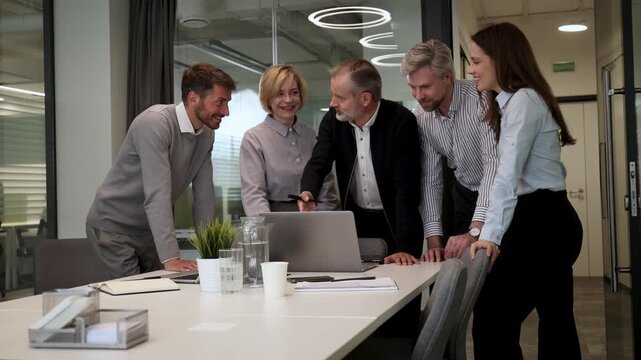 Business people discussing work together using a tablet and laptop taking notes in a modern office