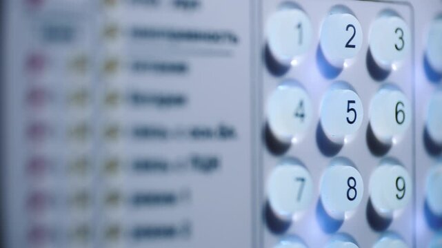 Finger pressing digit two button on electronic security system keypad for alarm activation.