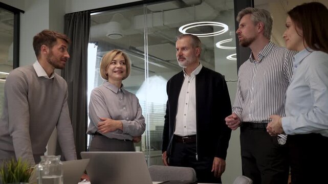 Five business people discussing work together in a modern office
