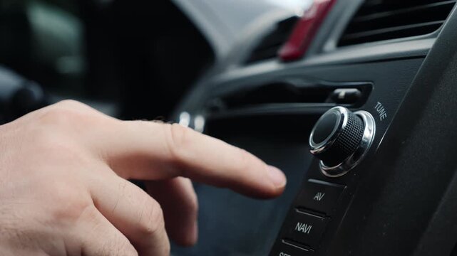 Close-up of hand adjusting car stereo knobs and pressing buttons for navigation and audio.
