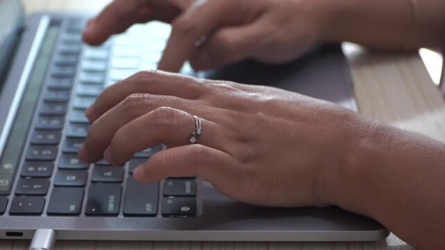Video footage of someone's hands typing on a laptop keyboard