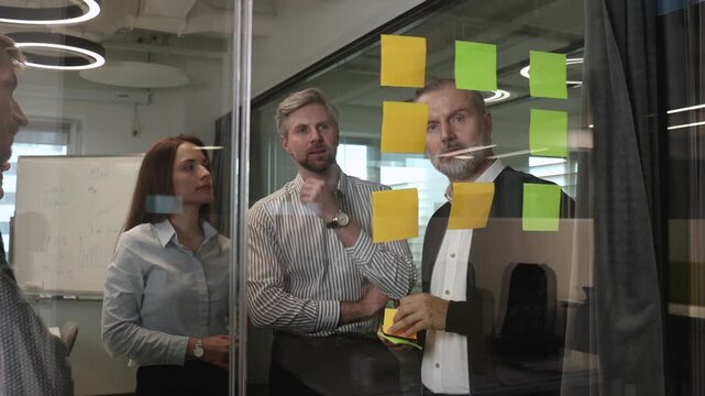 Creative group or business people planning innovation with sticky notes on glass wall.