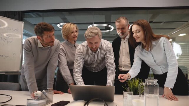 Business people discussing work together using a tablet and laptop taking notes in a modern office