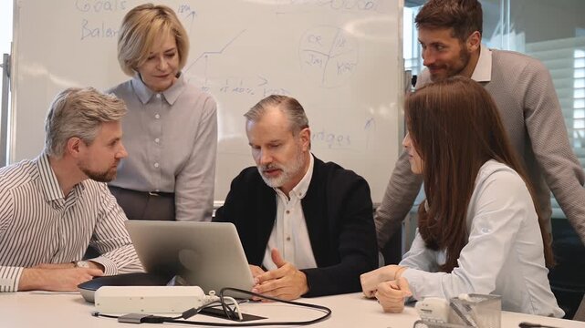 Successful businesspeople working in a coworking space working with laptop discussing strategy and business plan in modern office.
