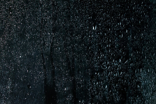 Transparent water droplets glass window overlay black background photo.