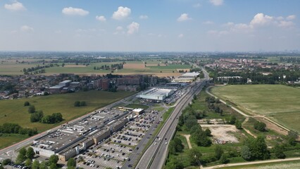 Fototapeta premium Aerial View of a Suburban Strip Mall and Highway: A vast expanse unfolds from above, showcasing a modern strip mall bustling with activity, its parking lot filled with vehicles.
