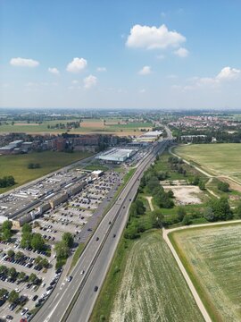Aerial View of Suburban Development: An expansive aerial perspective showcases a bustling suburban landscape featuring a major highway, a large commercial complex with a full parking lot.
