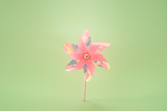 Pink holographic pinwheel bird deterrent on green background humane pest control solution for garden protection agriculture eco friendly vineyard orchard bird scarer minimalist outdoor tool,