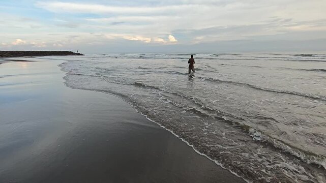 Local Fisherman Using Fishing Net in Shallow Waves on Tropical Beach