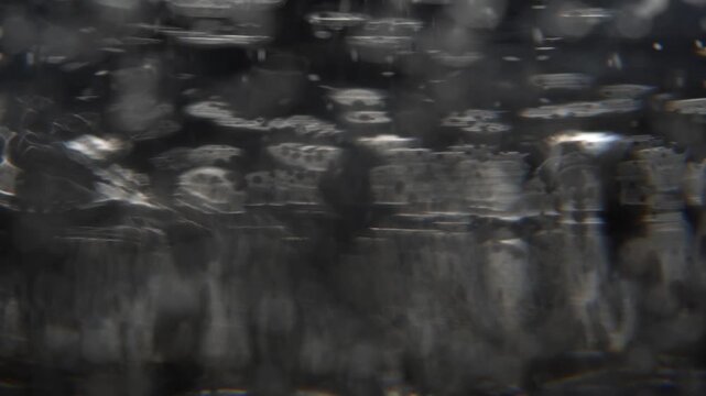 Macro view of bubbles in a glass of clear water, blurred dark background