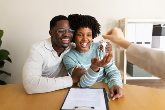 Happy couple receiving keys from real estate agent after signing a contract