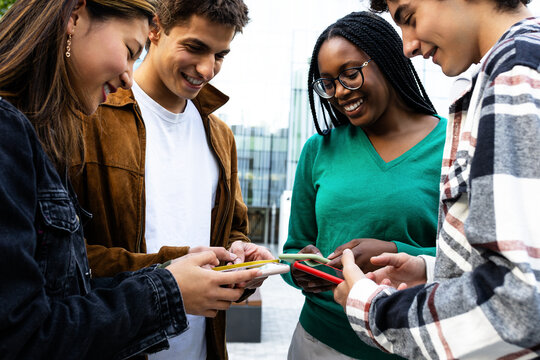 Group of students using smartphones together outdoors in university campus