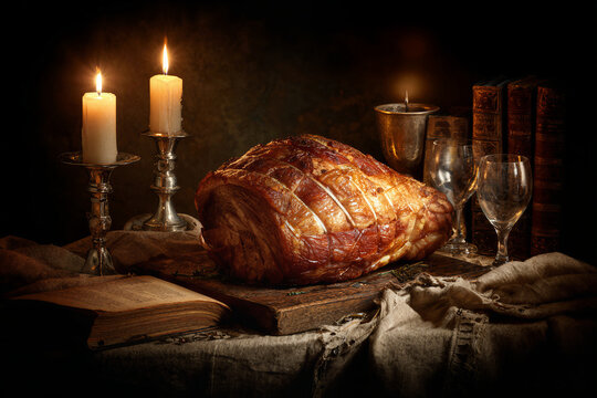 A large, perfectly roasted ham centerpiece with candles and wine glasses