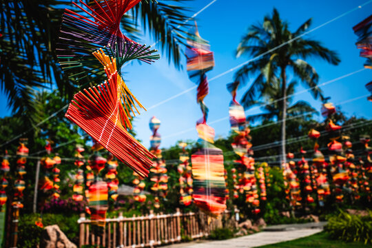 Colorful spiral wind spinners hanging from lines in a tropical garden park.