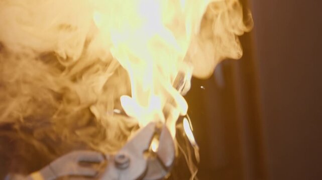 Knife is taken from furnace and quenched in bath by blacksmith, then ignites in workshop during quenching