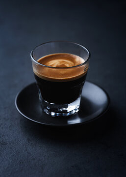 Coffee in glass cup on a dark stone background. Soft focus. Close up. Copy space.
